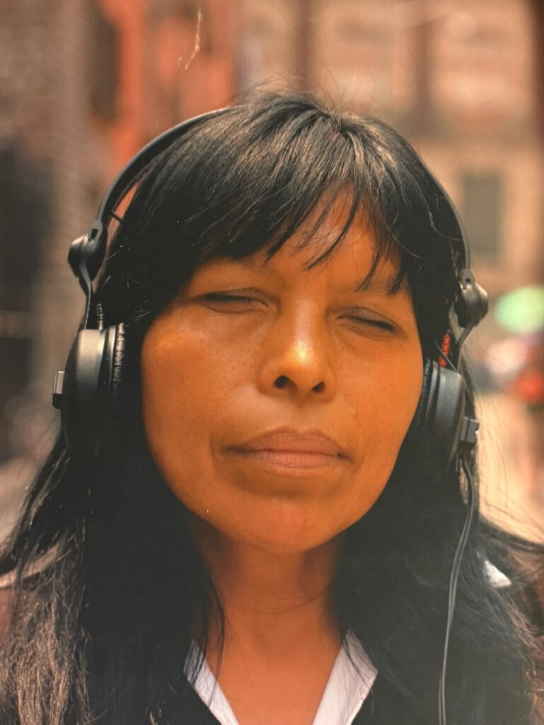 Das Foto des mexikanischen Künstlers Felix Blume zeigt eine mexikanische mittelalte Frau mit geschlossenen Augen mit Kopfhörern in im Klang versunkenen Zustand